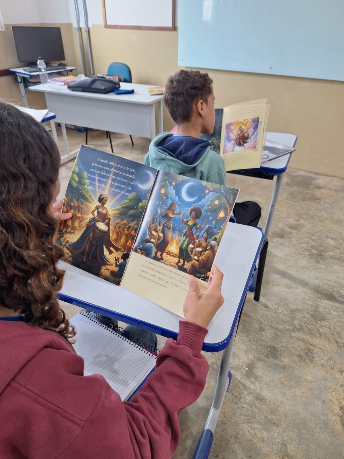 Estudantes, vistos de costas, lendo Adana em sala de aula